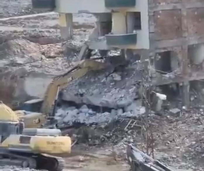 Hasarlı bina yıkılırken iş makinesinin üzerine devrildi