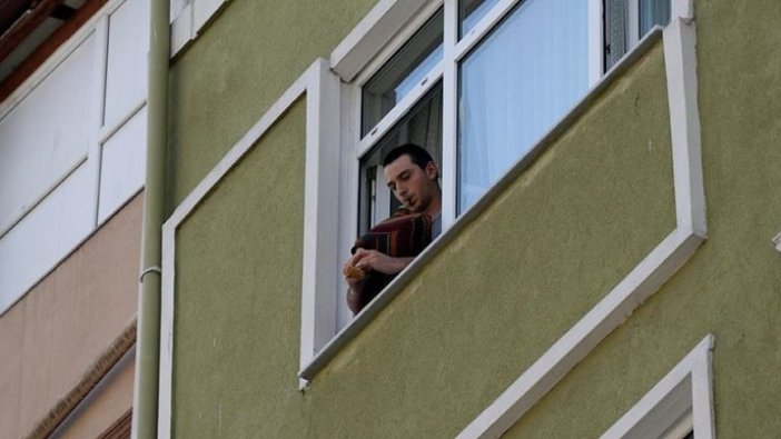 Evinin penceresinden çaldığı tulumla komşularına moral veriyor