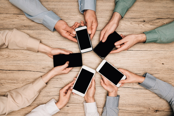 stock-photo-top-view-business-people-holding-smartphones-wooden-table-cropped-view.jpg
