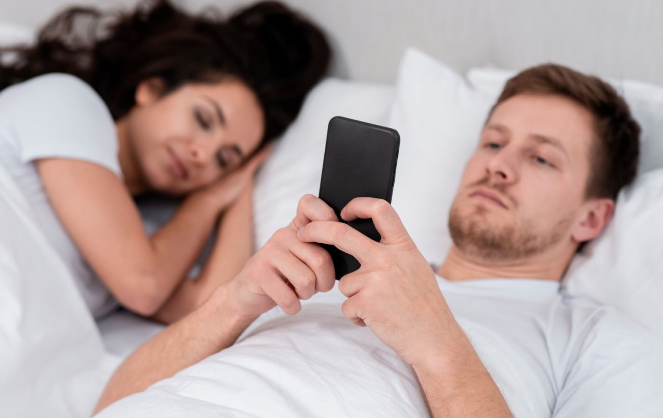 man-checking-his-phone-asleep-girlfriend-1300x820.jpg