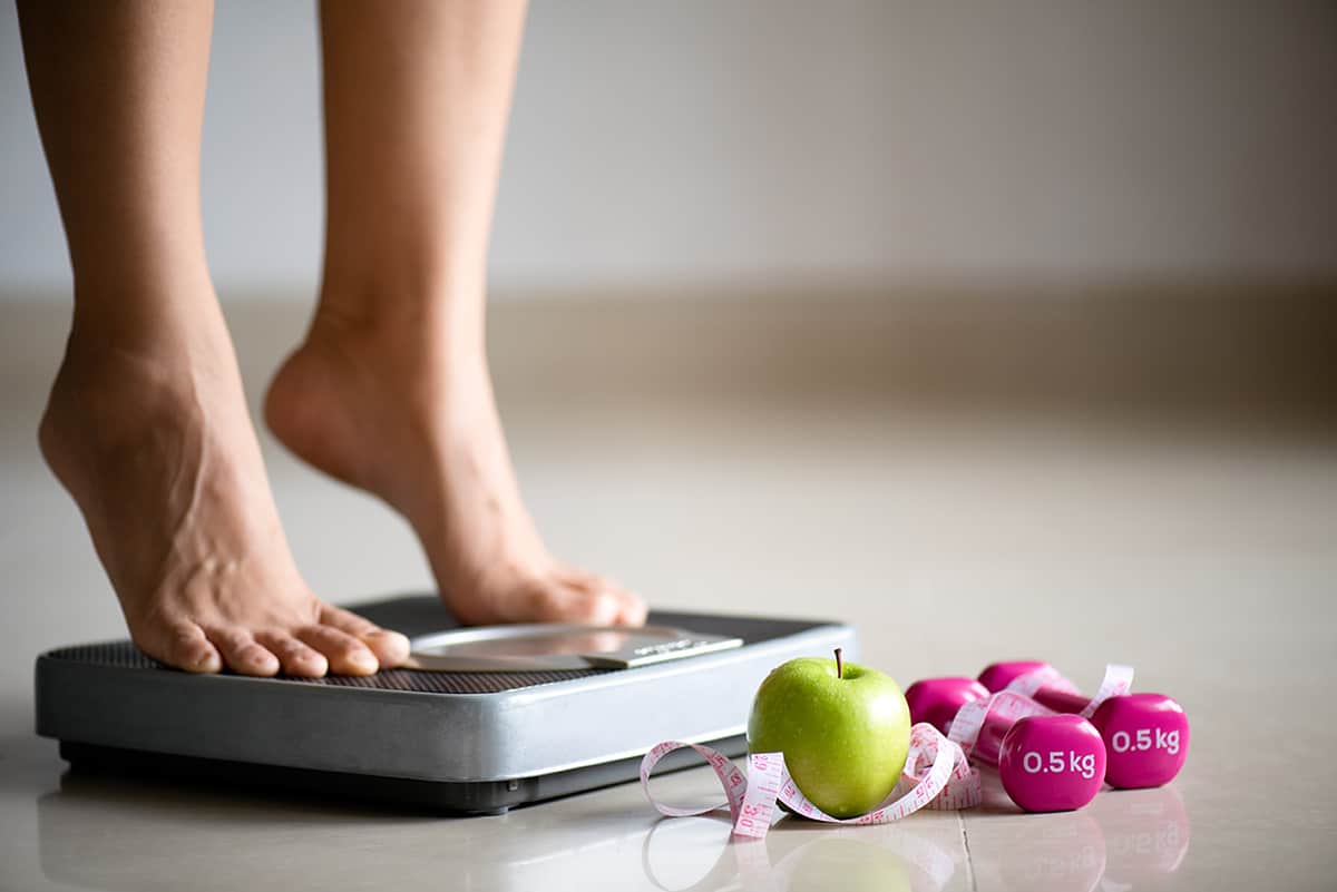 female-leg-stepping-on-weigh-scales-with-measuring-tape-1-copia-2.jpg